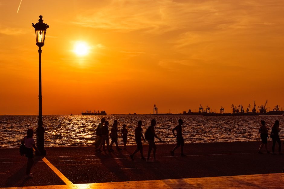 Silhouettes of people walking alongside the waterfront of Thessaloniki, Greece